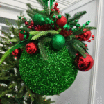 Red and green glitter hanging Christmas ornament with layered baubles and artificial foliage.